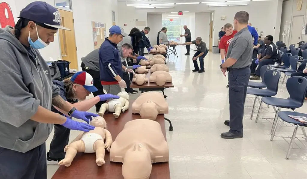 Healthcare professionals practicing life-saving skills during PALS certification training with pediatric and adult mannequins.