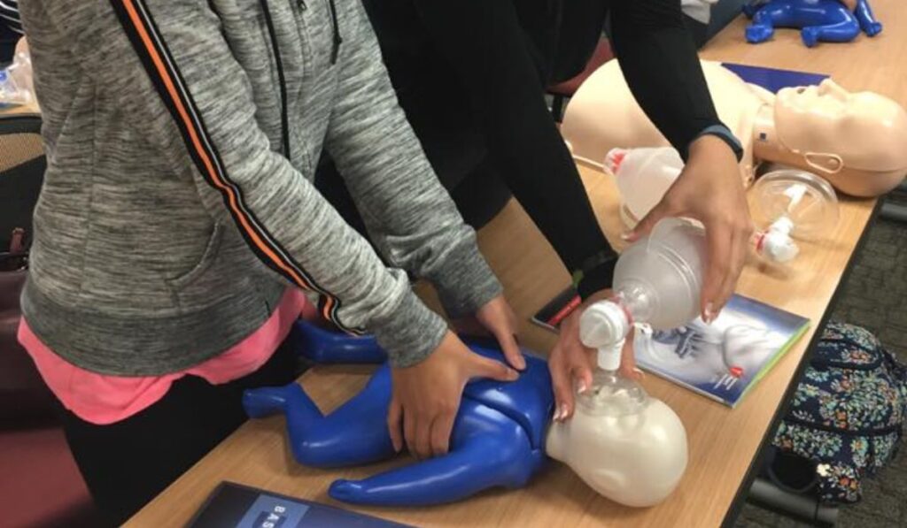2 people doing BLS training to a baby doll
