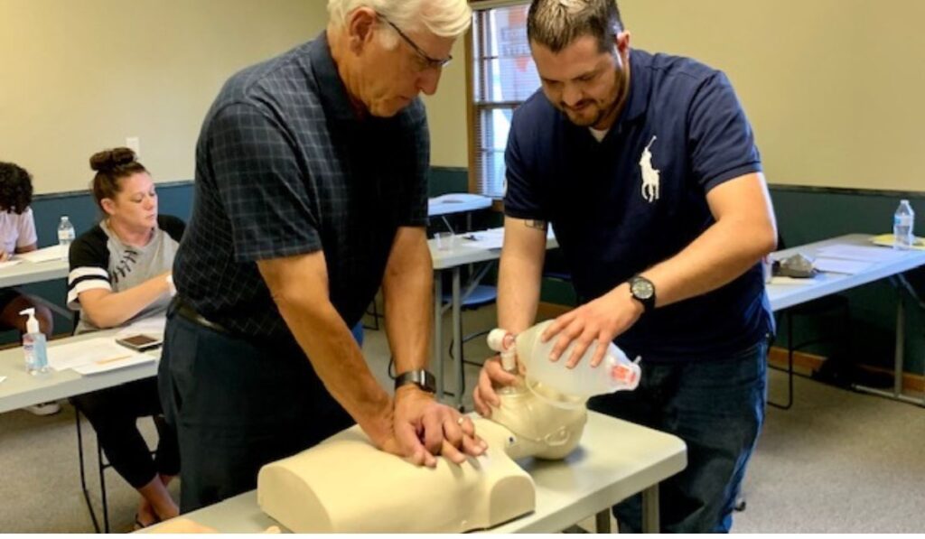 two men practicing bls on a mannequin
