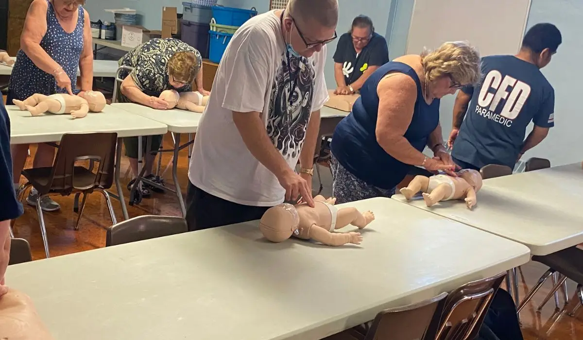 People practicing CPR on baby dolls