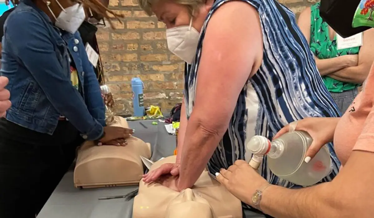 Two women performing CPR on a mannequin