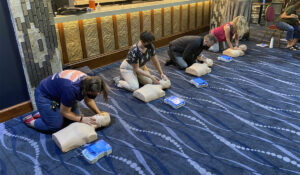 group of people kneeling on the floor practicing CPR on manikins