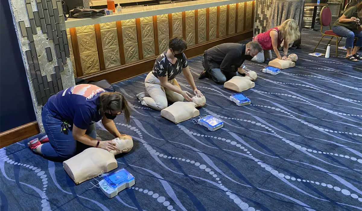 Group of people kneeling on the floor practicing CPR on manikins