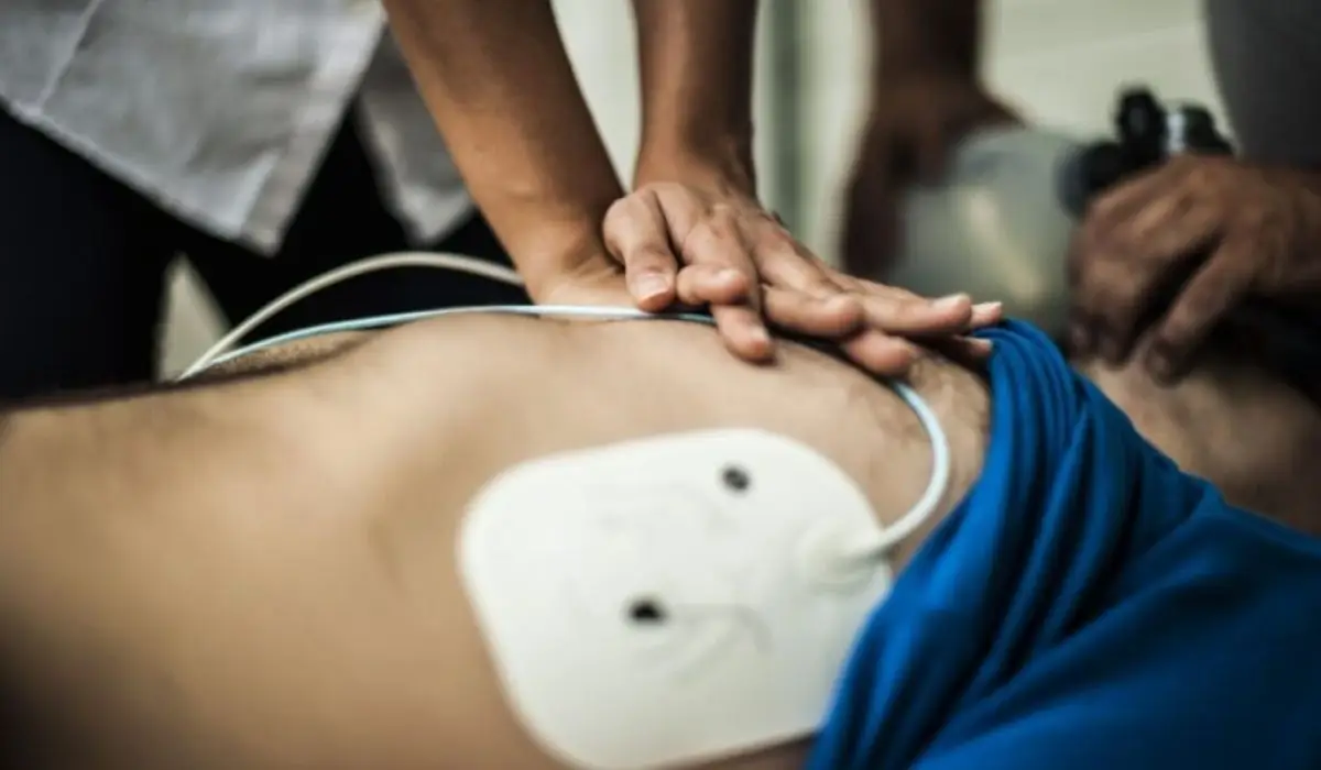 A Person Performing CPR On Another Person With An AED