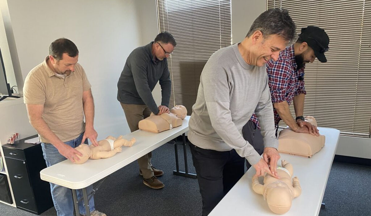 four men practicin CPR on dummies