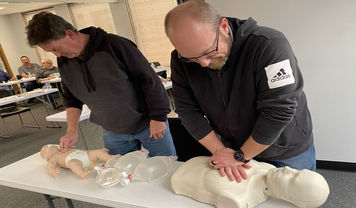 two men practicing CPR on a CPR doll