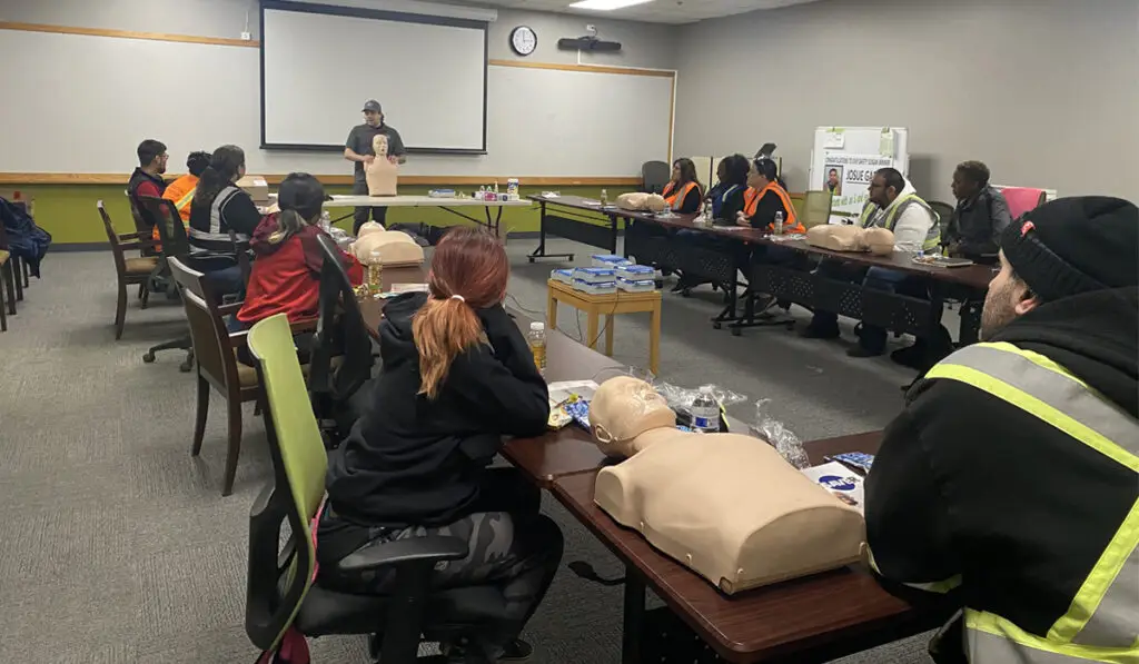 Adults gathered in a meeting room for an onsite training in CPR and BLS.