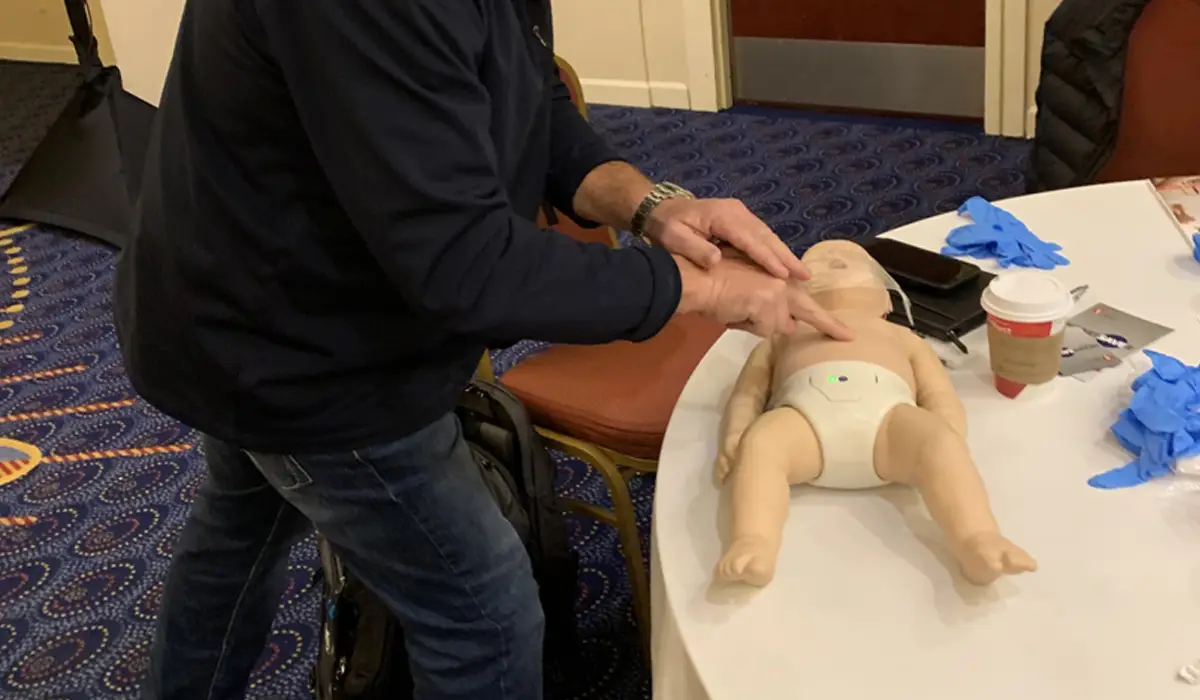 an old man practicing cpr on a baby dummy