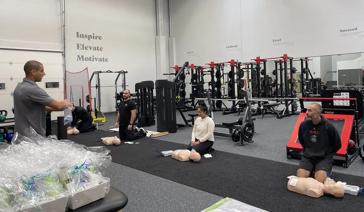 Adults gathered in a gym during CPR emergency training.