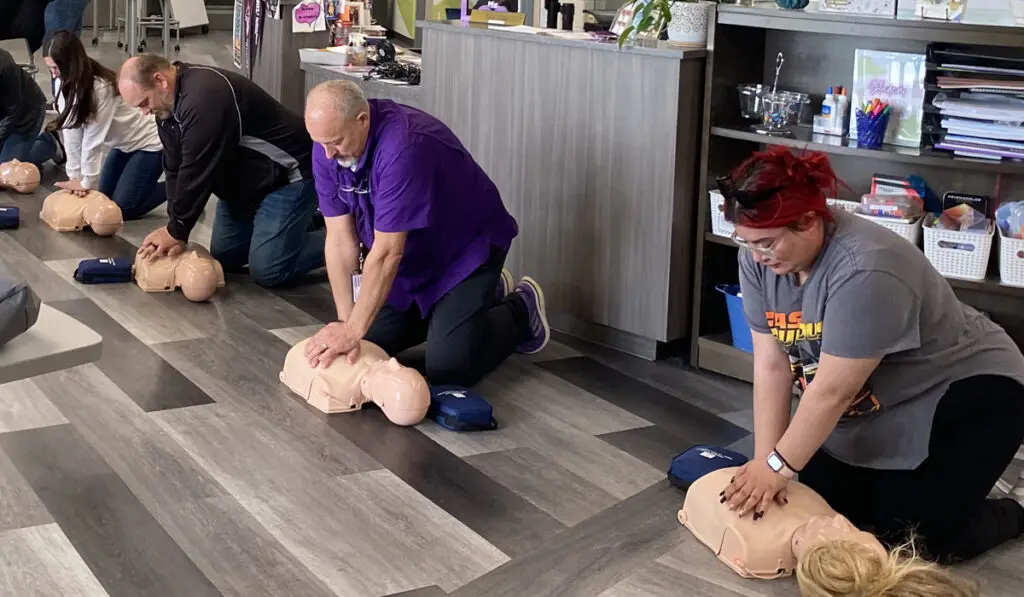 Adults in a small office room practices resuscitation during training.