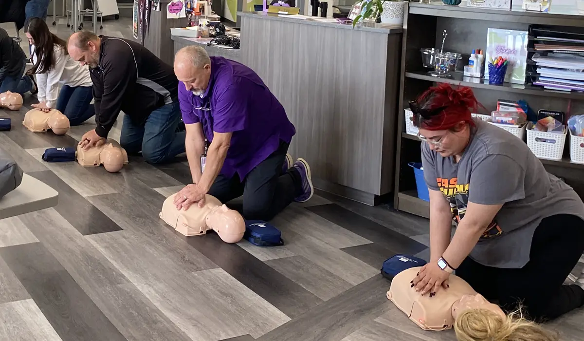 Adults in a small office room practices resuscitation during training.