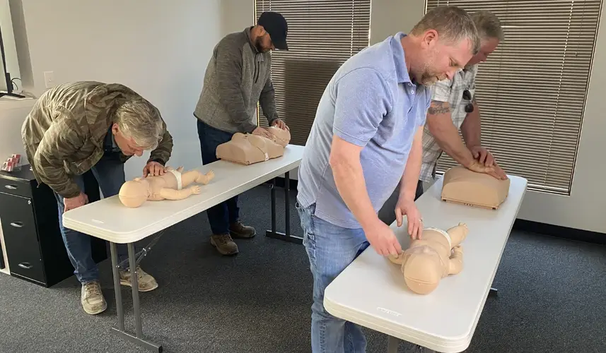 Four adults training in CPR on CPR dolls.