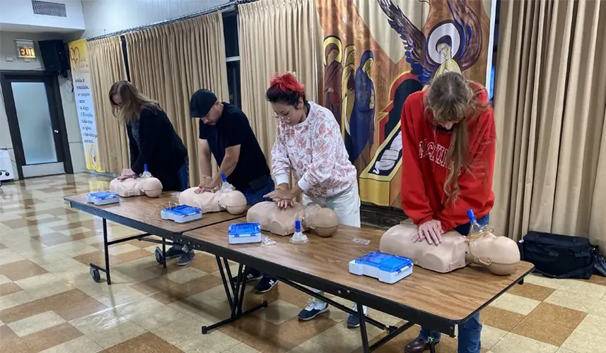 Four adults training in CPR and with an AED.