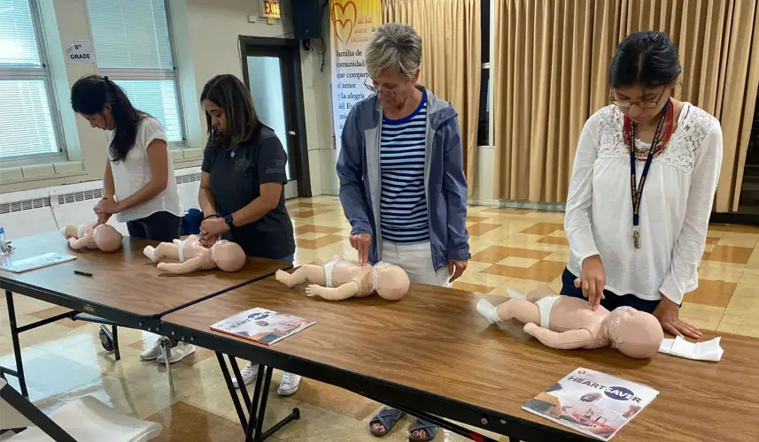 Four adults practicing CPR for infants.