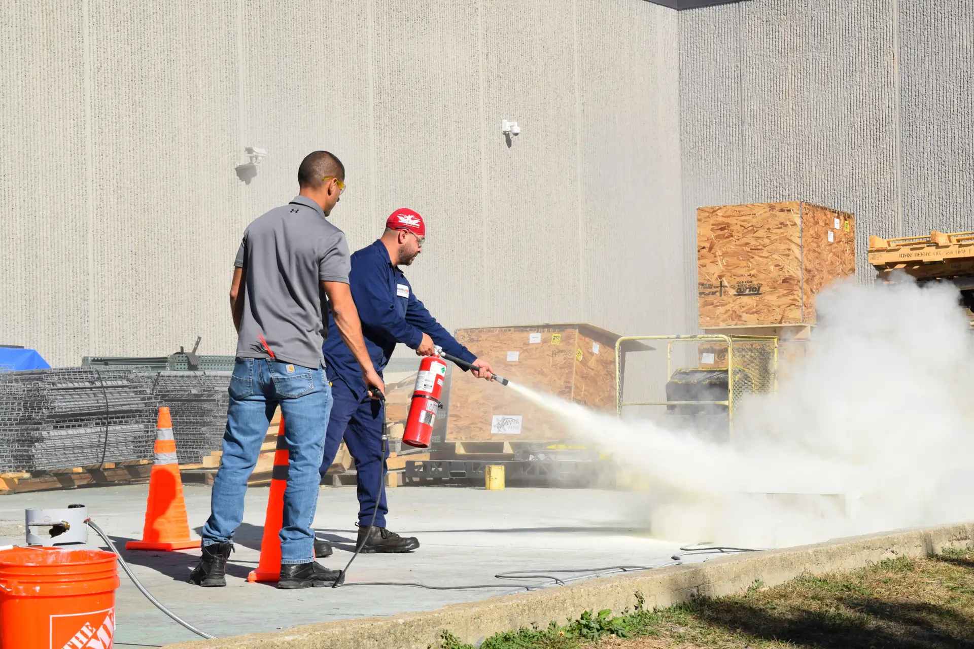 Fire extinguisher safety program training session with instructor demonstrating proper fire extinguisher use to a participant.