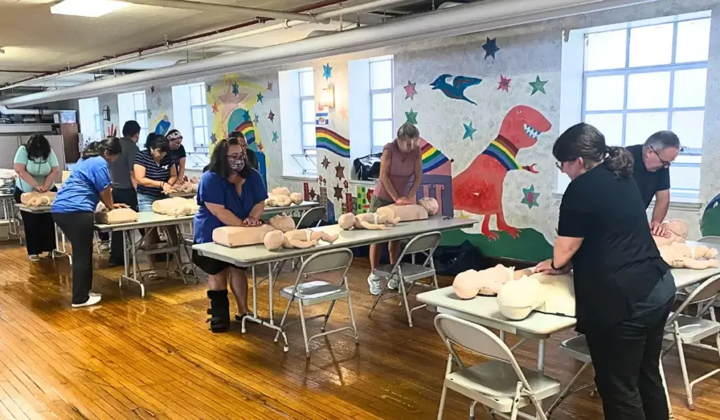 Childcare workers practicing CPR and BLS certification techniques during hands-on training.