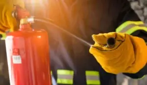 Fire extinguisher inspection being performed by a firefighter in Elmwood Park, Illinois, wearing protective gear and holding equipment during a safety check.