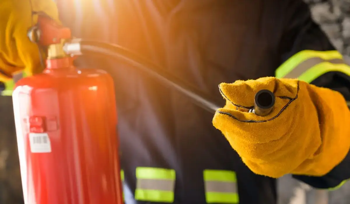 Fire extinguisher inspection being performed by a firefighter in Elmwood Park, Illinois, wearing protective gear and holding equipment during a safety check.