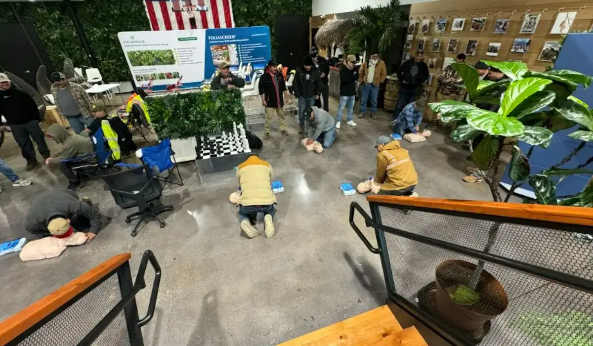 Employees in an industrial workplace setting practicing CPR on manikins during a group safety training session focused on building a safety culture.