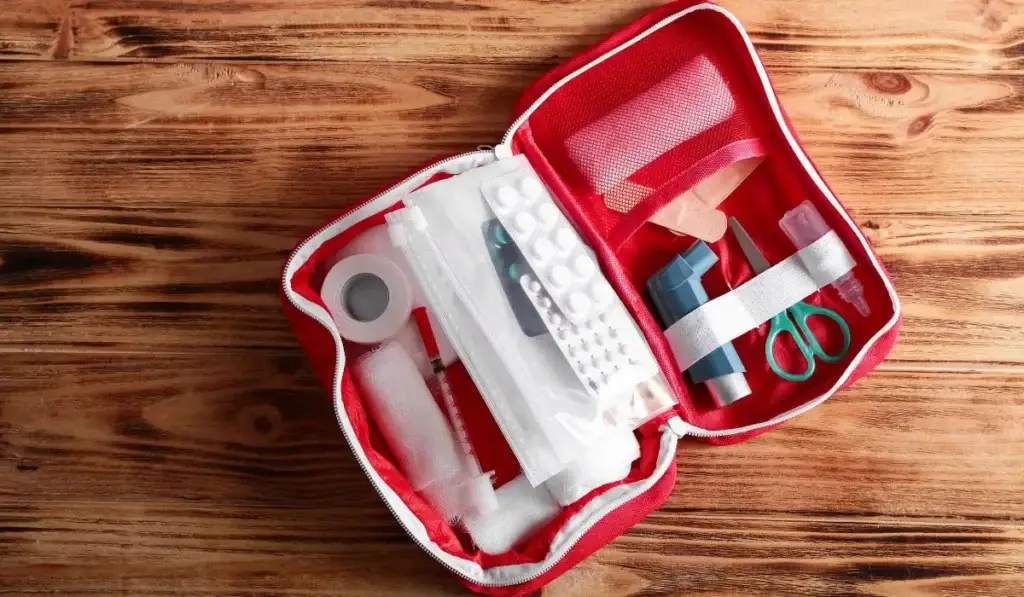 Open emergency kit with workplace first aid supplies including bandages, tape, inhaler, and scissors—representing OSHA-compliant preparedness.