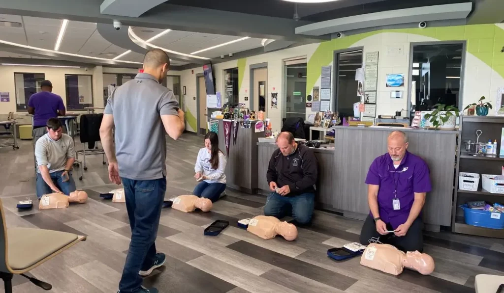 Healthcare workers practicing CPR with AED devices during BLS Recertification class in Illinois professional setting.
