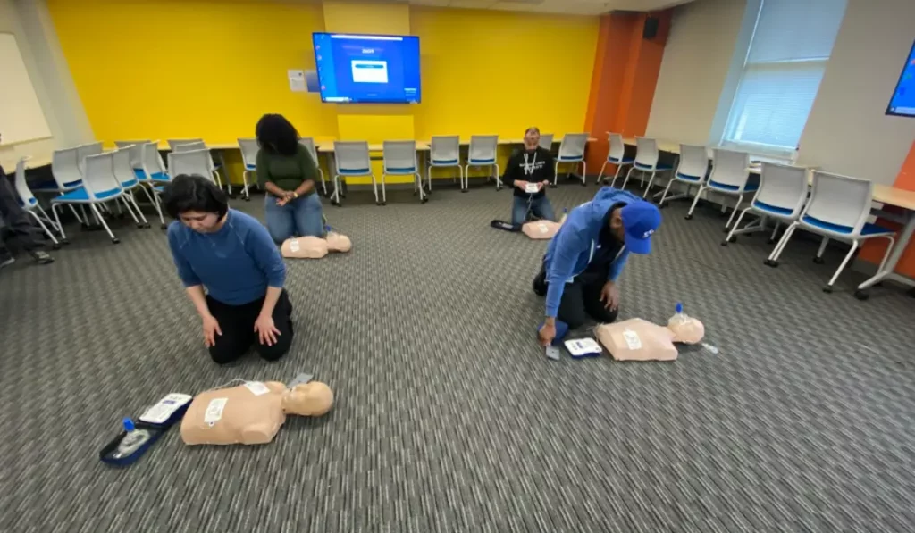 Group of adults practicing CPR and AED skills during ACLS or BLS Certification classroom training session.