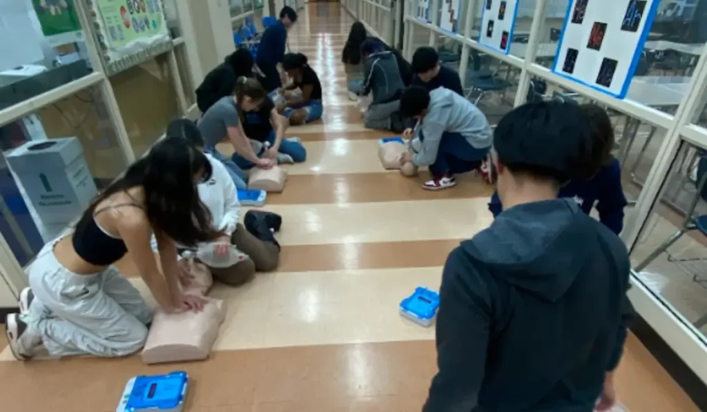 Students in CPR Training practicing chest compressions and AED setup during a live instructor-led certification course.