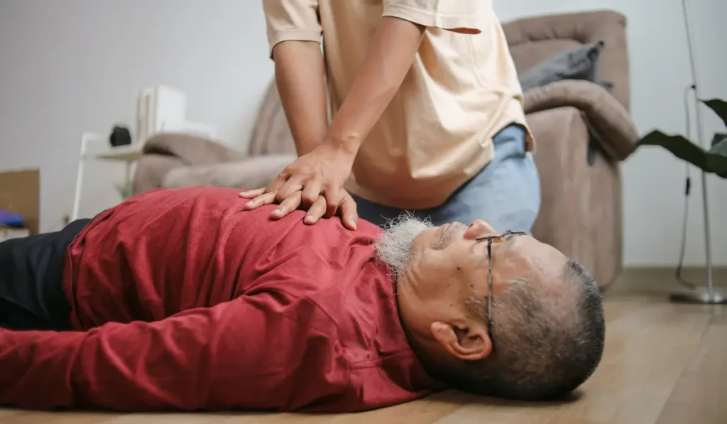Caregiver performing CPR for seniors on an elderly man at home during a cardiac emergency with chest compressions