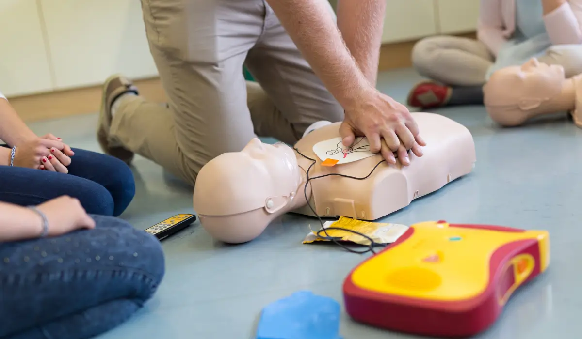 Instructor demonstrating proper chest compressions and AED pad placement during hands-on CPR training session correcting common CPR myths
