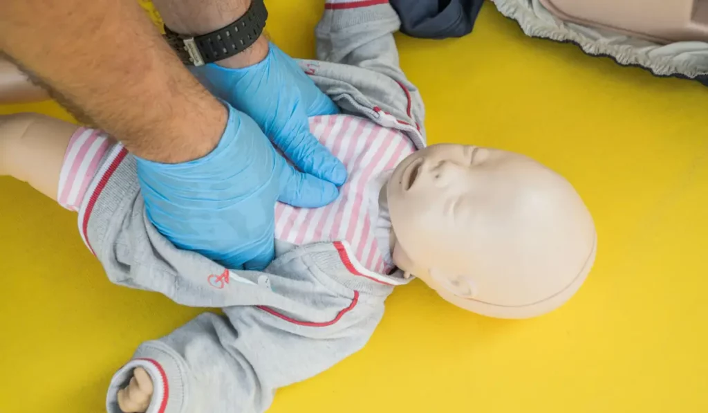 NRP Certification in Chicago training showing neonatal chest compressions on a newborn mannequin